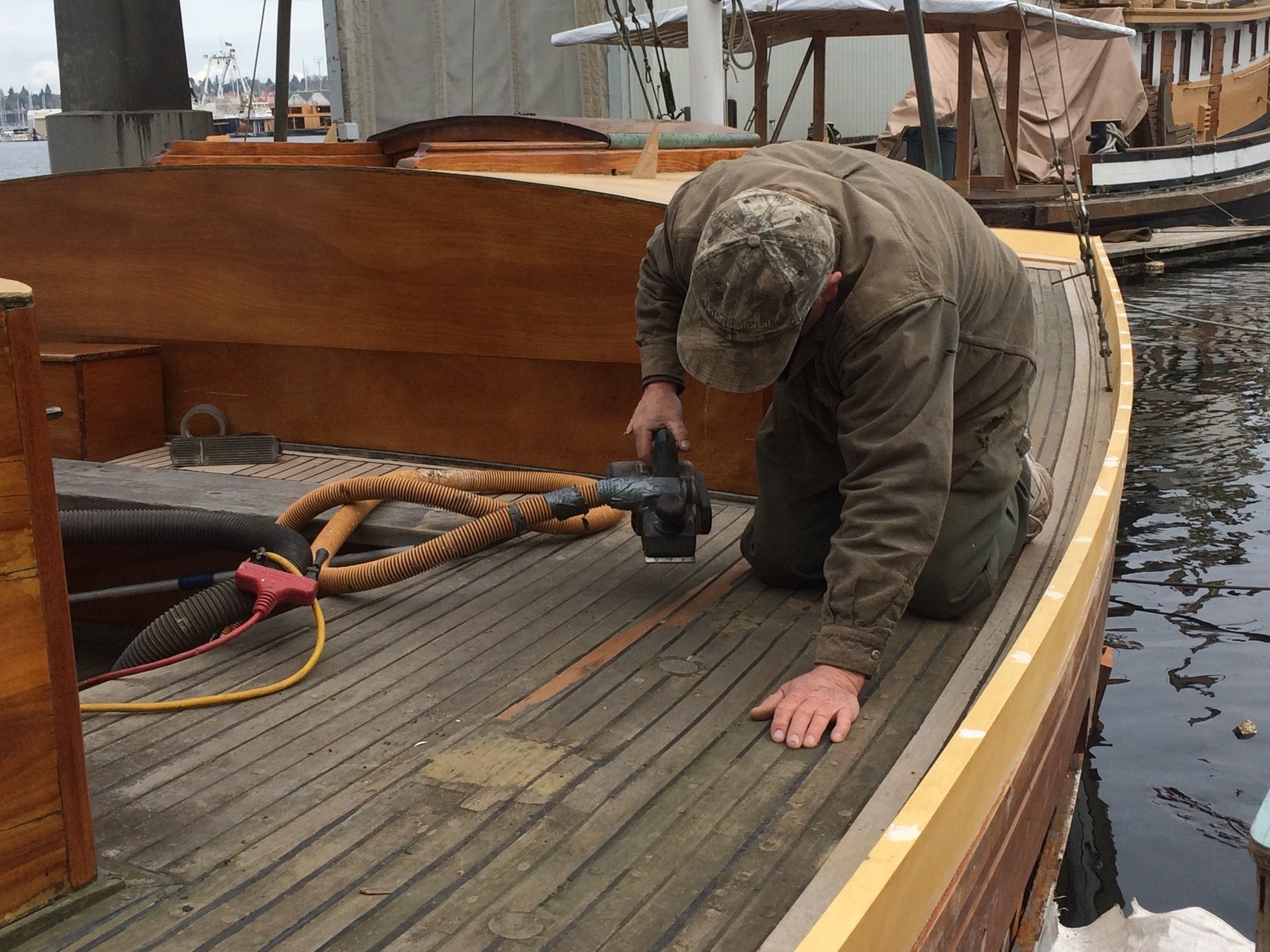 A craftsman carefully restores the wooden deck of the classic 1946 Philip Rhodes-designed Merry Maiden, revealing the meticulous care required to maintain these historic sailing vessels.