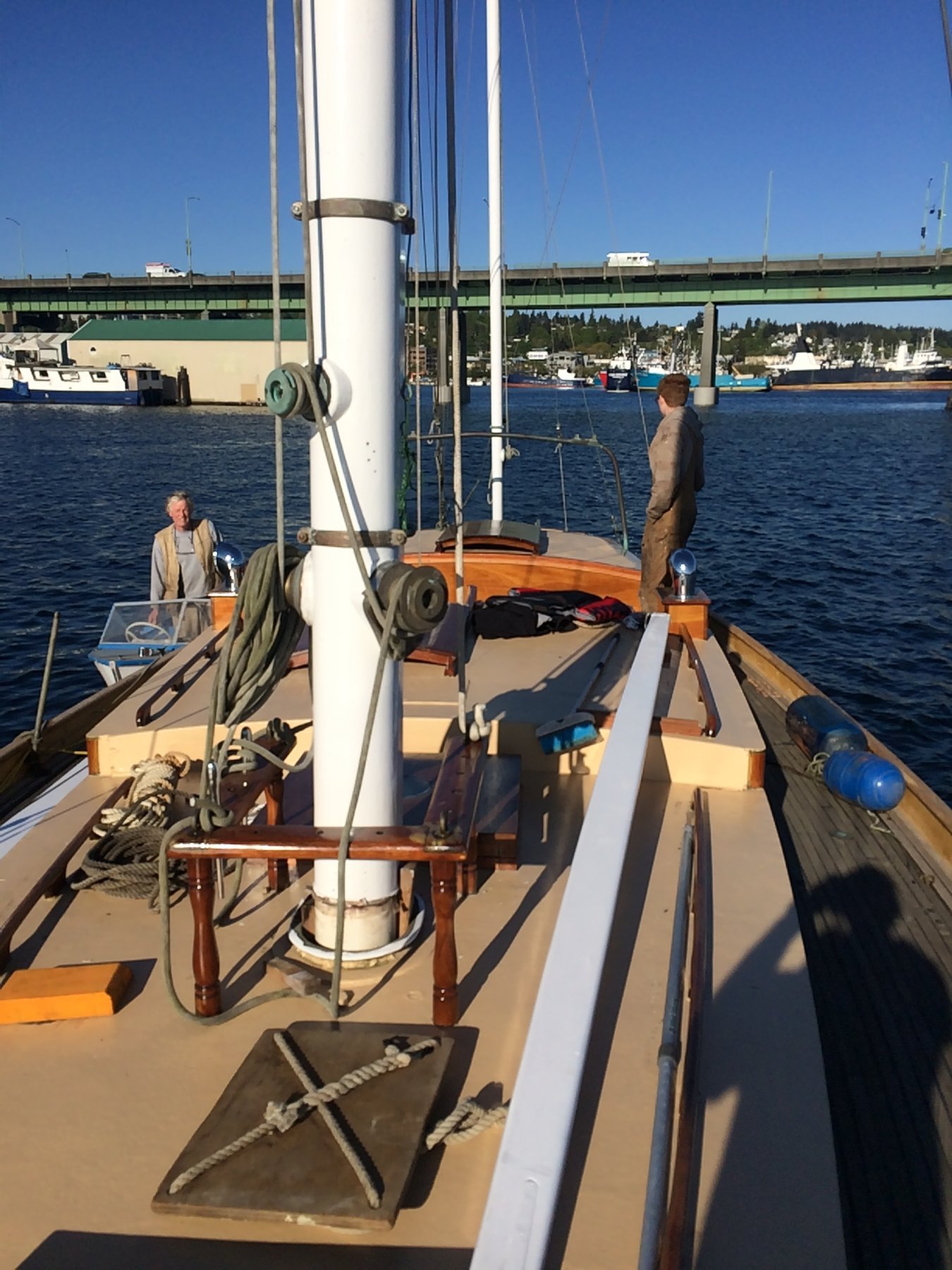 The classic lines of Merry Maiden's boom and rigging frame a sunny day on Puget Sound, with her crew enjoying the calm waters near the Washington shoreline.