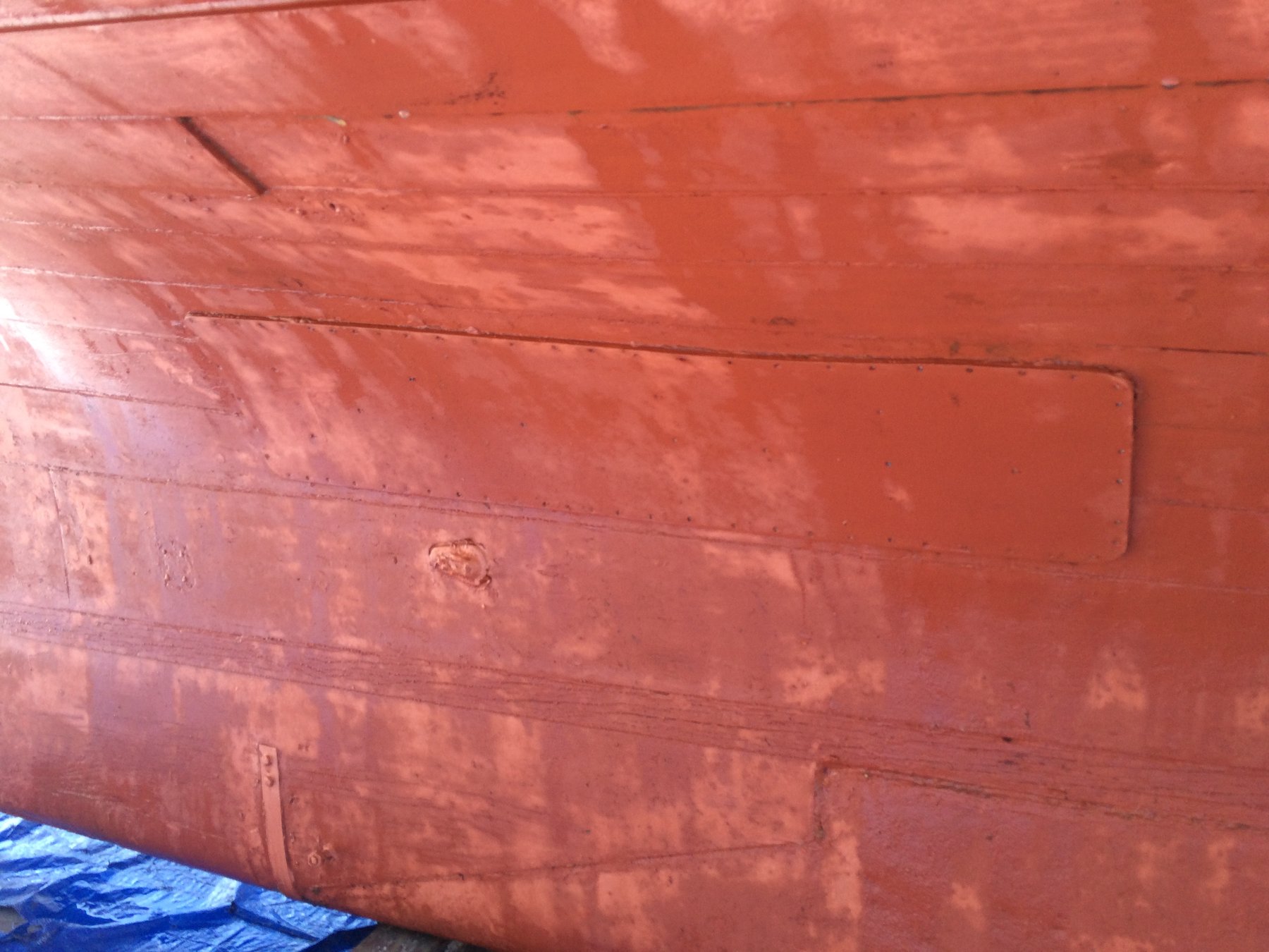 The weathered hull of Merry Maiden reveals decades of character and care, her red-painted planking showing the patina of a classic 1946 Philip Rhodes design maintained with devotion in the Pacific Northwest.