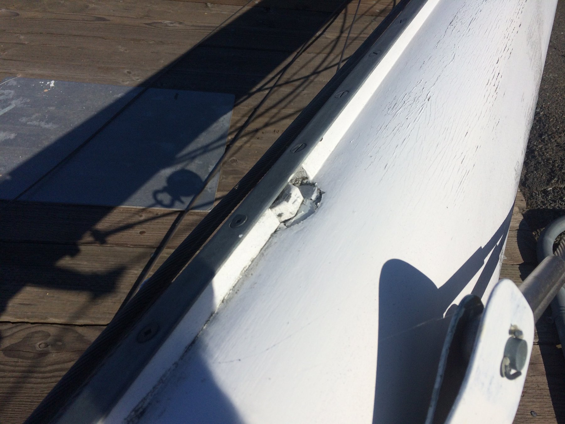 Overhead view of Merry Maiden's white hull and dark rubbing strake, revealing weathered paint and hardware details as the classic 1946 Rhodes design rests at the dock in Puget Sound.