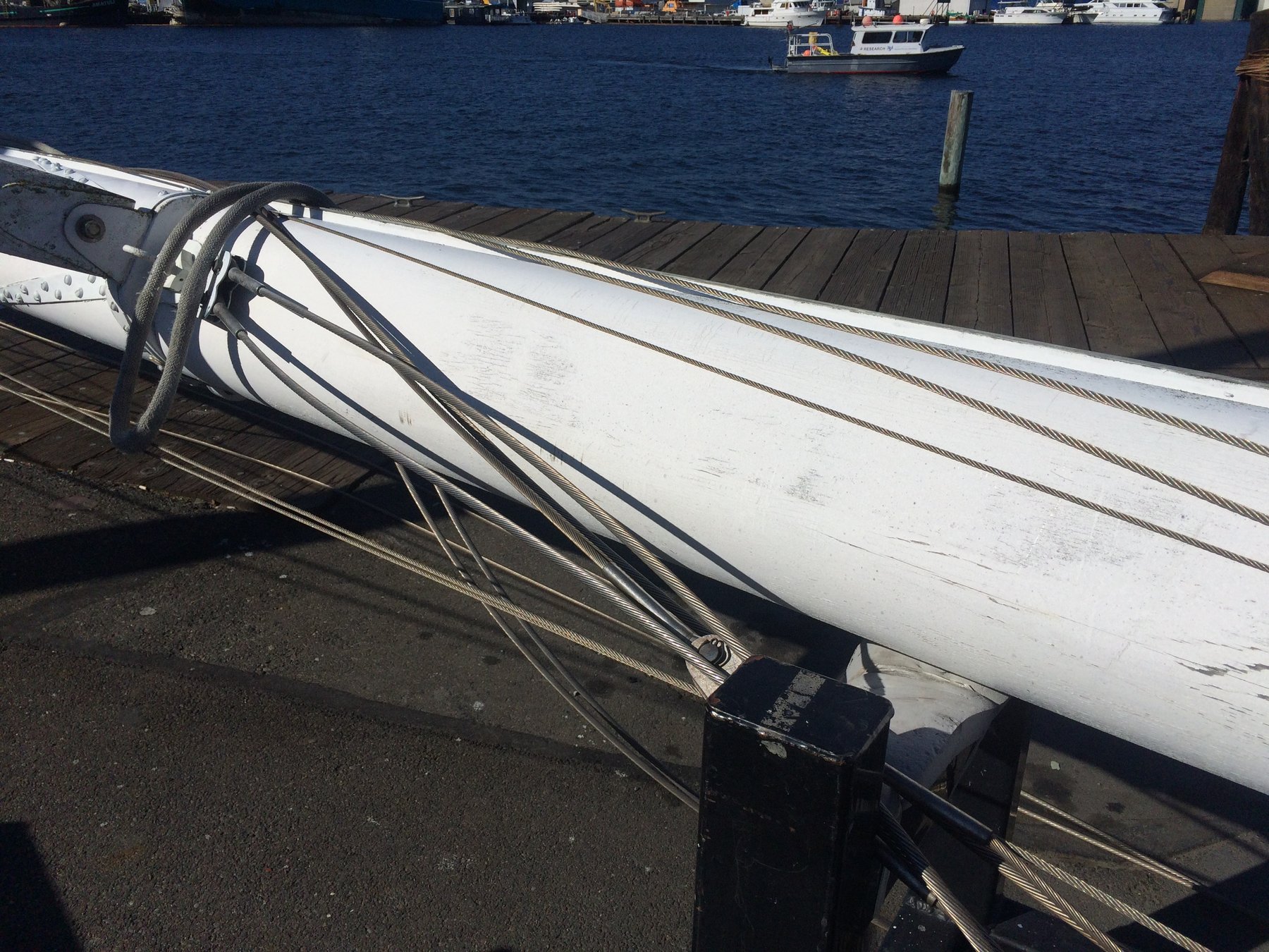 The graceful boom of the classic 1946 Philip Rhodes-designed Merry Maiden rests secured at the dock, her white hull and rigging catching the afternoon sun against the deep waters of Puget Sound.