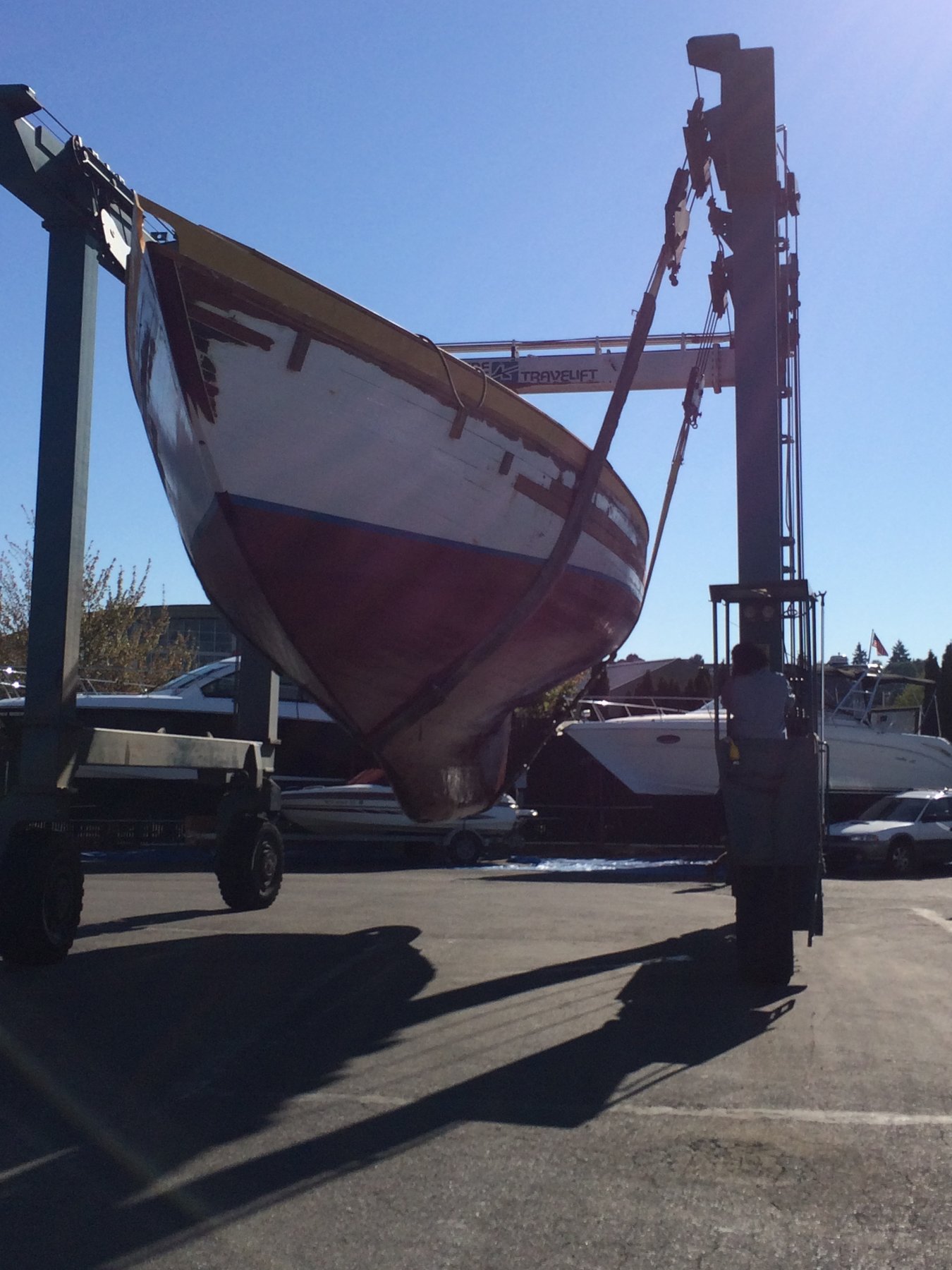 The classic 1946 Philip Rhodes-designed Merry Maiden sits hauled-out in a Puget Sound boatyard, her burgundy hull and white cabin gleaming against the clear Pacific Northwest sky.