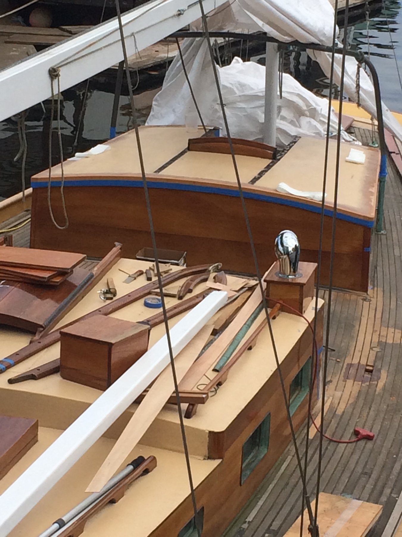 The classic lines of Merry Maiden, a 1946 Philip Rhodes design, rest peacefully at the dock in Puget Sound, her varnished teak and cream hull reflecting decades of thoughtful stewardship.