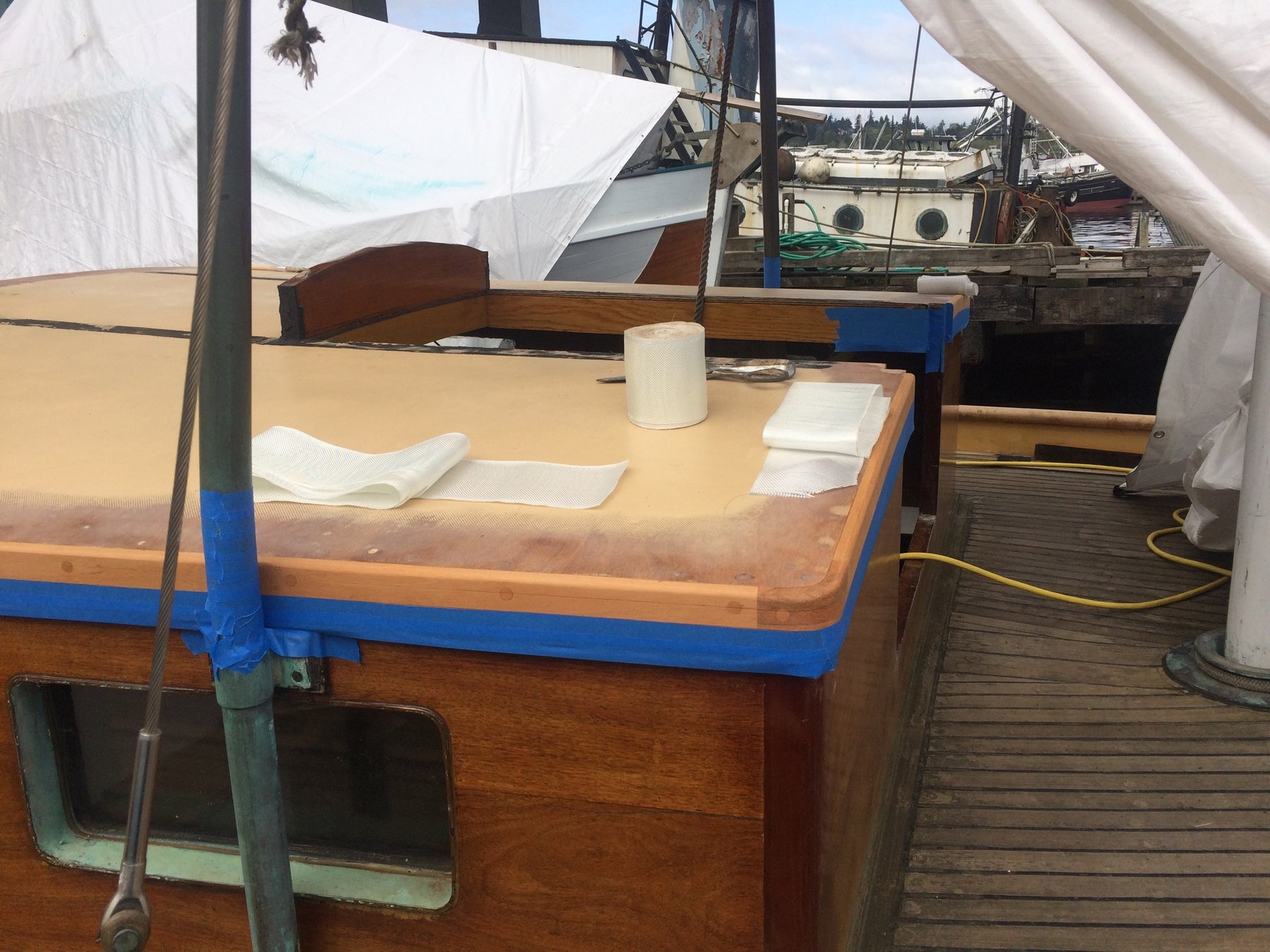 The spacious cabin of Merry Maiden reveals her classic 1946 design, with warm teak furnishings and traditional wooden details complemented by practical blue trim and canvas awnings.