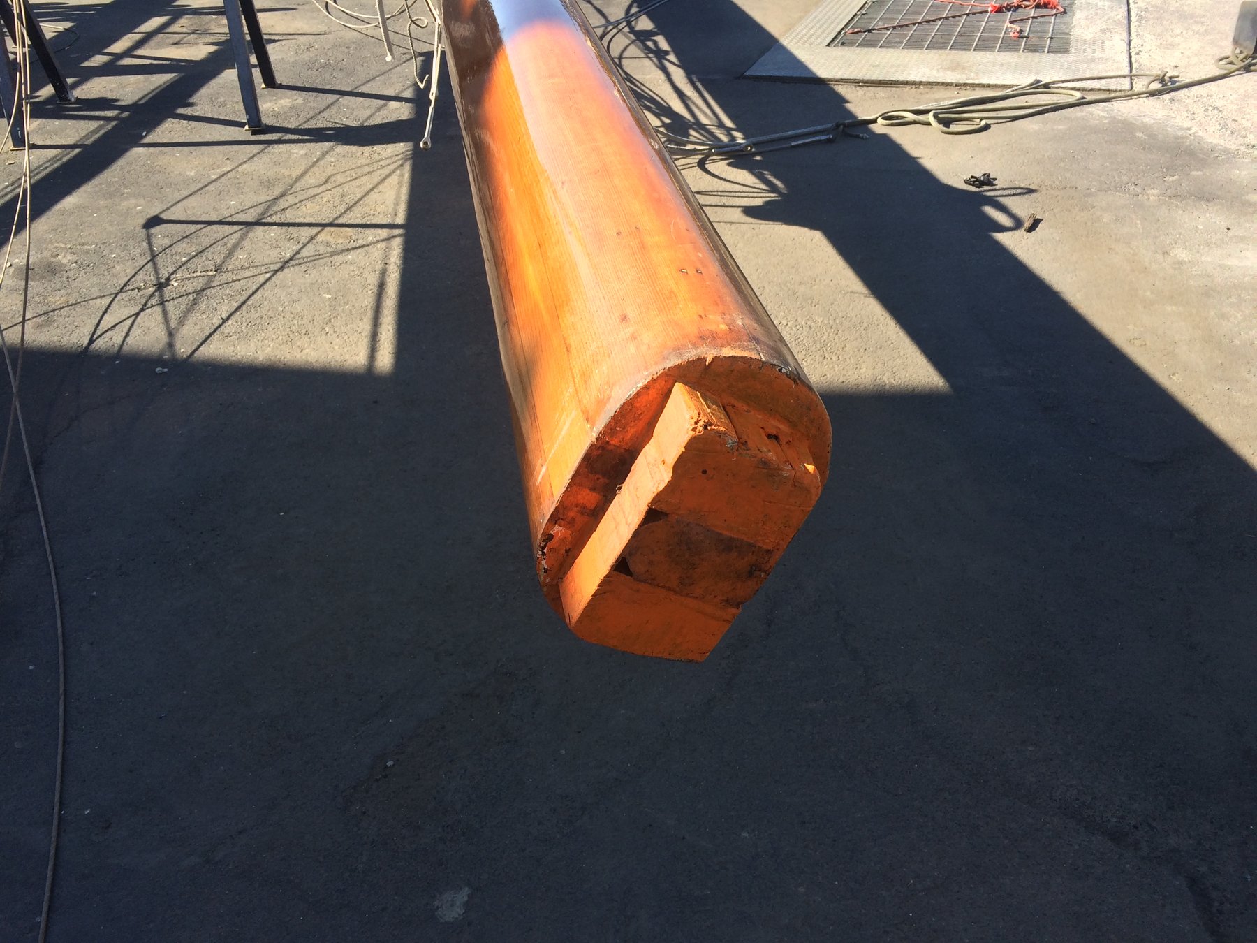 A wooden spar from the classic 1946 Philip Rhodes-designed Merry Maiden lies in the Puget Sound shipyard, its warm grain and patina evidence of both age and careful craftsmanship awaiting restoration.